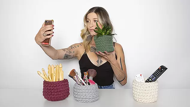 Anne Galante fazendo selfie com vaso de plantas em crochê